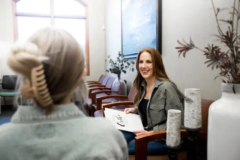 Team member discussing paperwork with a patient in a bright consultation room.